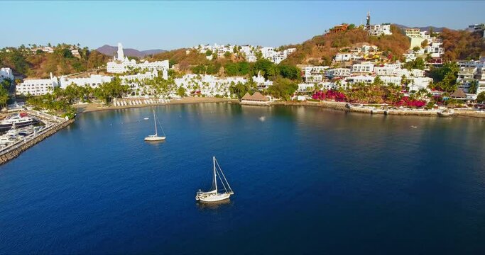 Aerial View of Sailboats near Beach Resorts with Mountains and Bay Background