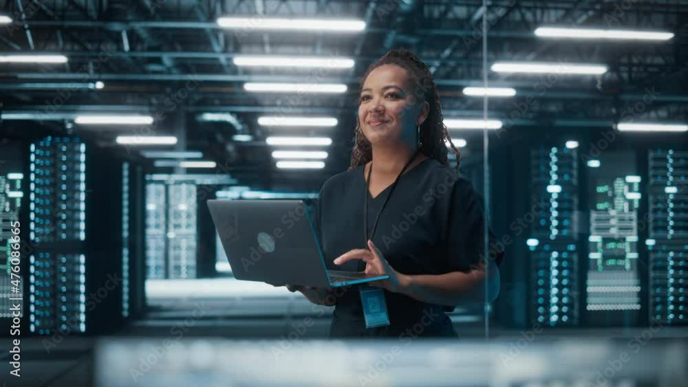 Poster Portrait of Successful African American Female IT Specialist Using Laptop, Standing in Data Center. System Administrator Works on Web Services. Cloud Computing, Server Analytics, Cyber Security
