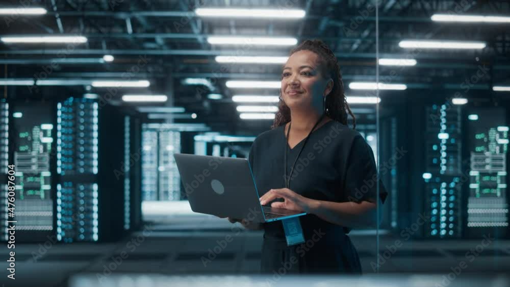 Poster Portrait of Successful African American Female IT Specialist Using Laptop, Standing in Data Center. System Administrator Works on Web Services. Cloud Computing, Server Analytics, Cyber Security