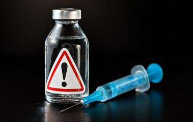 Vaccine bottle with red triangle exclamation mark sign on label, blue hypodermic syringe needle...