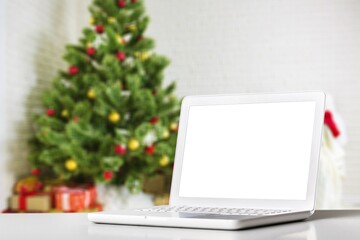 Blank display screen laptop computer on white wood table. Modern cozy comfortable home living room with Christmas decor.