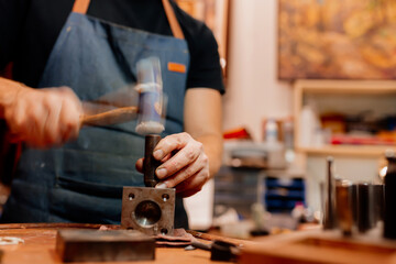 jeweler using his tools to shape a ring. worker using a rubber hammer.
