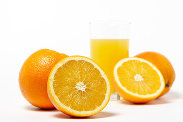 Freshly squeezed orange juice on a white background. A glass of orange juice and a cut orange next to it. Refreshing natural fruit juice
