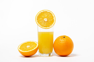 Freshly squeezed orange juice on a white background. A glass of orange juice and a cut orange next to it. Refreshing natural fruit juice
