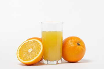 Freshly squeezed orange juice on a white background. A glass of orange juice and a cut orange next to it. Refreshing natural fruit juice