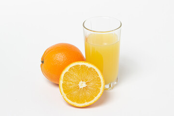 Freshly squeezed orange juice on a white background. A glass of orange juice and a cut orange next to it. Refreshing natural fruit juice