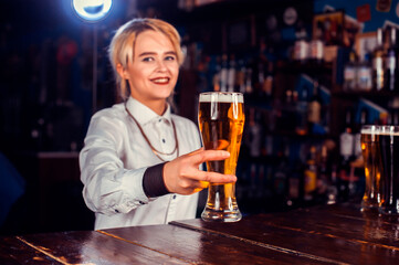 Girl barman mixes a cocktail behind the bar