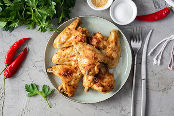 A hearty meal for lunch: chicken baked in the oven on a plate on a gray background, grilled chicken on a plate, top view.