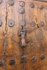 Metal knocker in the shape of a hand on the door of a house in a town in the north of Palencia, Spain