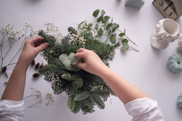 Woman decorated a Christmas table decoration. Hands close-up. Master class on making decorative ornaments. Christmas decor with their own hands. Flower shop. Christmas composition of fir branches.