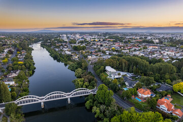 Aerial drone view at sunset, looking up the Waikato River towards the CBD, over the city of Hamilton (Kirikiriroa) in the Waikato region of New Zealand.