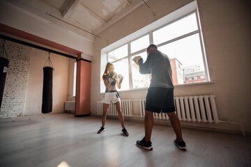 Female martial arts fighter practicing with trainer, punching taekwondo kick pad exercise kicking. Training of kickboxer woman strikes with bare foot mitts punching bag kicking shield