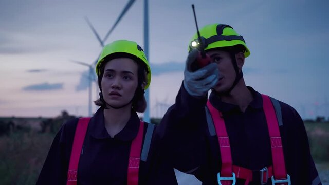 at twilight ,Two maintenance engineers in safety gear working at height walking to the wind turbine to check the operation of the wind turbine, clean energy concept, renewable energy, save the world.
