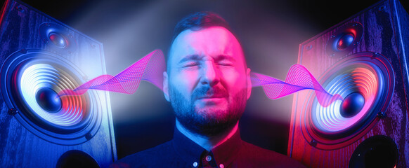 Speakers with sound wave in neon light and man portrait. Discomfort from listening to loud music. Hearing damage concept. - obrazy, fototapety, plakaty