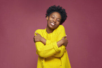 Love yourself, self acceptance. Smiling young african american woman embrace herself, closed eyes....