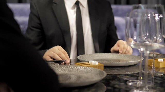 An elegant couple on a date in an elite restaurant on a romantic date.A man in a business suit is having dinner with a beautiful girl in an evening dress.A blind date.Against the background of glasses