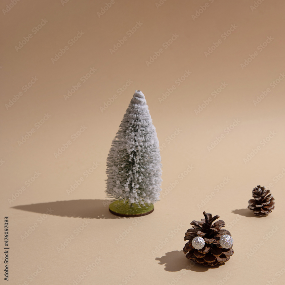 Poster new year's tree sprinkled with snow and cones with sharp shadows on a beige background