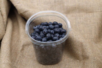 Large selected fresh juicy blueberries in a tray on burlap