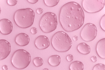 A pattern of pink doses of acid, hyaluronic moisturizing serum or gel on a monochrome background. Abstract backdrop pattern. Beauty product wallpaper. Cosmetics or healthcare protection concept. 