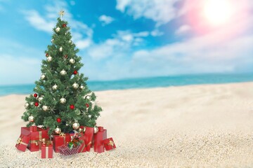 Christmas tree on the beach. Gift Boxes on sand beach shore. Decorated pine or fir tree.