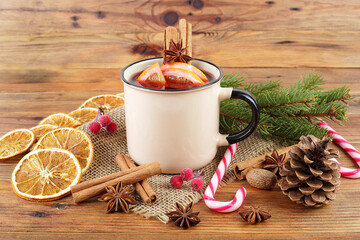 Delicious Christmas hot mulled wine, green pine tree branch and spices on wooden background.