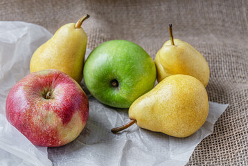 ripe juicy apples and pears on sackloth on white parchment