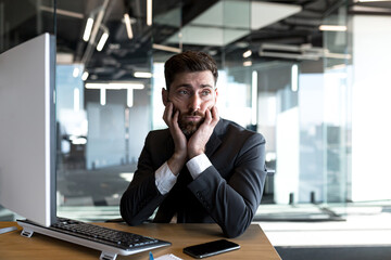Tired and pensive businessman, working in the office at the computer, a man stressed at work and...