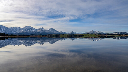 der hopfensee am frühen morgen mit spiegelung der berge im wasser