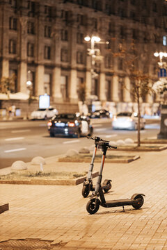 Electric motorized rental scooters parked on urban city street near sunset selective focus low angle