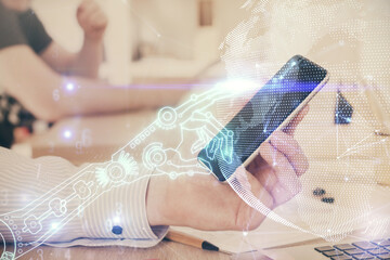 Double exposure of man's hands holding and using a digital device and tech theme hologram drawing....