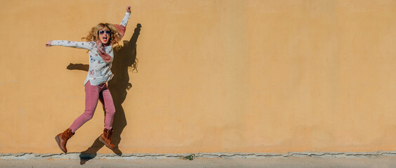woman jumping for joy with outdoor wall background
