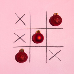 Red Christmas decoration tictac toe game on pink background. New year minimal creative idea. Flat...