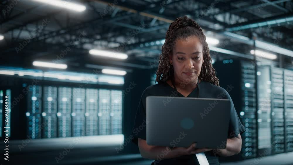 Aufkleber african american female it specialist using laptop computer, standing in big warehouse data center. 