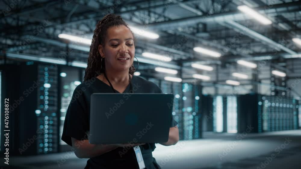 Aufkleber african american female it specialist using laptop computer, standing in big warehouse data center. 