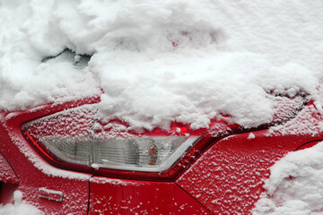 Hood red metal car with headlight in the snow close up, Light passenger car luxury class under snow cover.