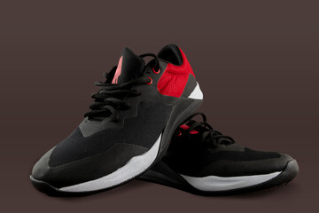 Black and red sports tennis shoes on a brown background, with space for text