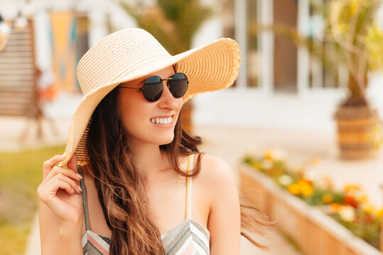 Photo of young beautiful woman with sunglasses and hat walking the streets of town