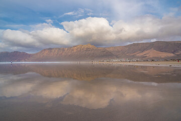 View of the beautiful Famara Beach (Playa de Famara), with a nice reflection of the sky on it's sands - Lanzarote, Canary Islands, Spain