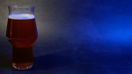 Beer glass filled against gray background with blue lights