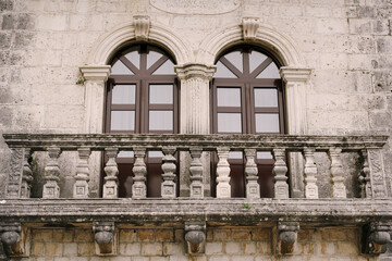 Stone balcony with carved balusters and brown glass doors with pilasters