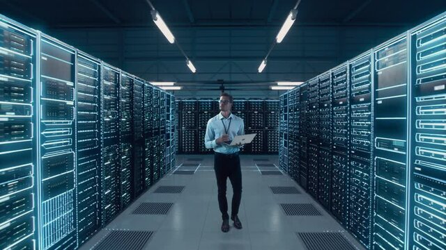 Futuristic Animated Concept: Big Data Center Chief Technology Officer Using Laptop Standing In Warehouse, Activates Servers, Information Digitalization Starts. SAAS, Cloud Computing, Web Service