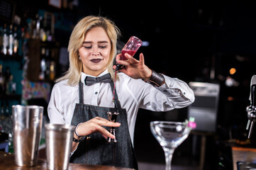 Charming woman bartending mixes a cocktail at the nightclub