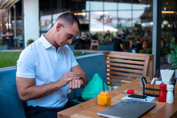 Businessman sitting in a cafe and checking messages on his smartwatch