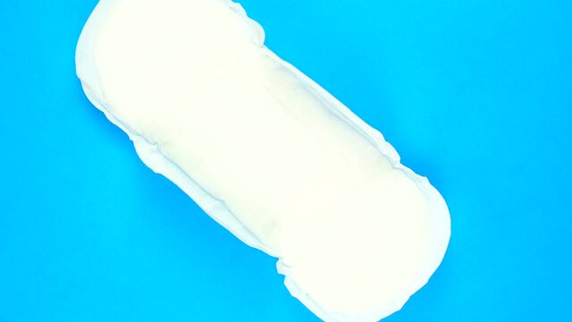 Female menstrual pad rotates on blue background