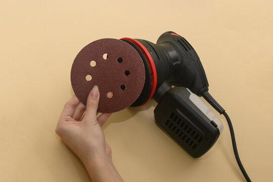 Eccentric orbital sander, woodworking. installation of the grinding wheel on the sole of the grinder.