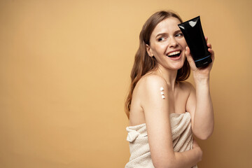 Fototapeta premium The woman uses a new body skin cream, moisturizing and scrub. The model shows cosmetics after the spa.