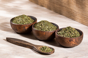 Dried organic tarragon leaves in three wooden bowls - Artemisia dracunculus