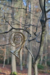 Ein Waldhorn in Wald, an einem Baum dessen Äste sehr ähnlich mit den Röhren des Instrument sich...