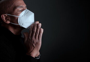 man praying to God with face mask on black background stock photo	
