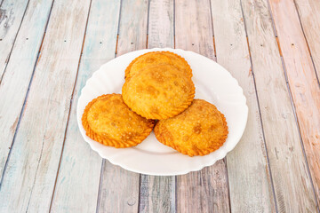 Empanadas stuffed with pulled chicken meat with parsley on white plate and blue flowers